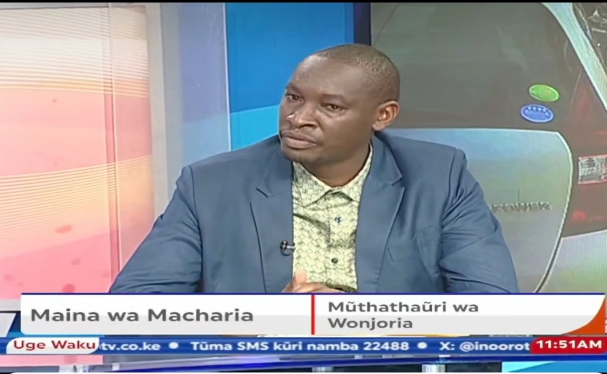 Patrick Maina Macharia in the Inooro TV studio, captioned Maina wa Macharia, Mũthathaūri wa Wonjoria